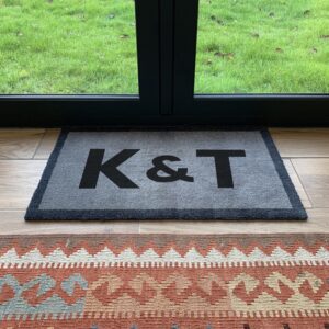 a grey doormat with a personalised monogram printed onto it in black